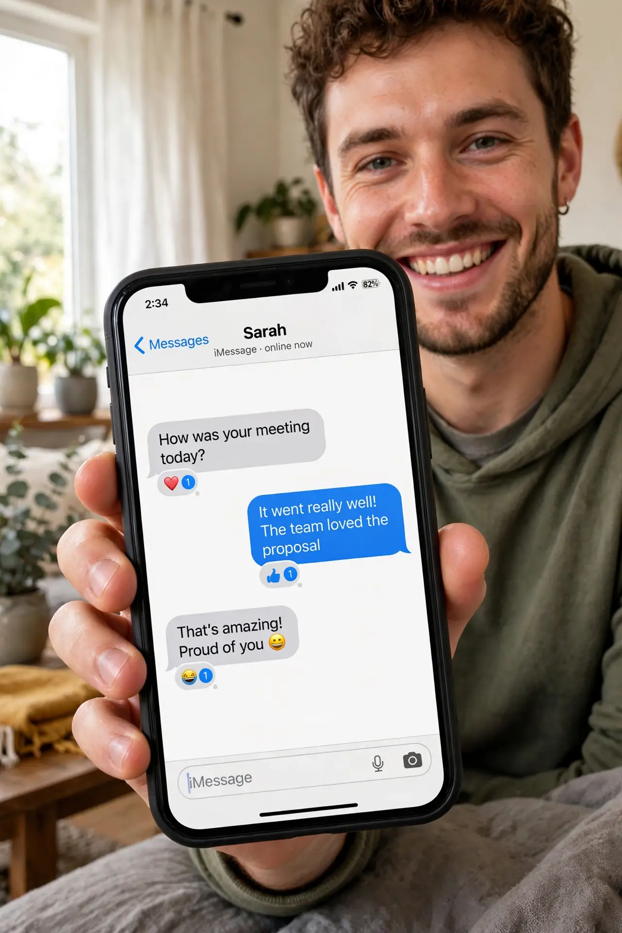 a person holding a real iPhone showing a Messages conversation with tapback reactions on several messages, the person smiling, cozy home setting. No black screen, no blank white sc.